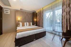 Una habitación de hotel moderna con una cama grande, una mesita y vistas al exterior.