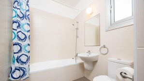 Un baño con bañera, lavabo, inodoro y espejo.