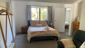 A bedroom with a bed, a nightstand, a dresser, a chair, and a window with curtains. - Close to the river, 11 TeAho  is 
a family lodge with plenty of character  (Tūrangi)