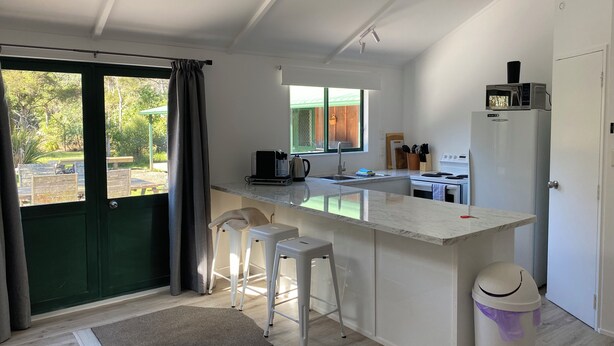 A modern kitchen with a large island, white countertops, and a view of the outdoors. - Close to the river, 11 TeAho  is 
a family lodge with plenty of character  (Tūrangi)