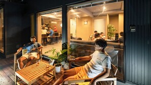 Un interno moderno con arredi in legno, un divisorio in vetro e piante da interno.