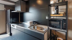 Una cucina moderna con lavello in acciaio inossidabile, forno a microonde integrato e macchina da caffè su un ripiano in legno.