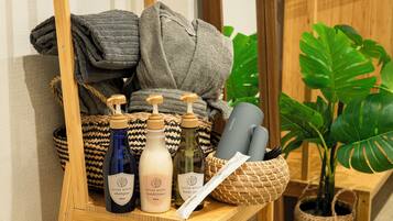 A shelf with toiletries including shampoo, conditioner, body soap, and a toothbrush, alongside towels and a plant.