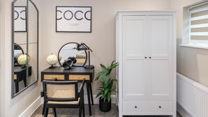 Un dormitorio moderno con un amplio armario, un escritorio con un globo terráqueo y auriculares, y un espejo.
