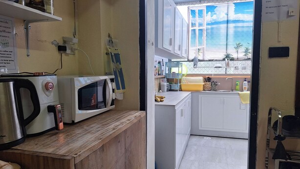 Une petite cuisine équipée avec un four à micro-ondes, une machine à café et un évier. Une fenêtre offre une vue sur la plage.