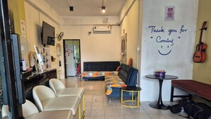 Une chambre d’hôtel avec un lit, un canapé, une table à manger et une petite table sur laquelle se trouve une guitare.