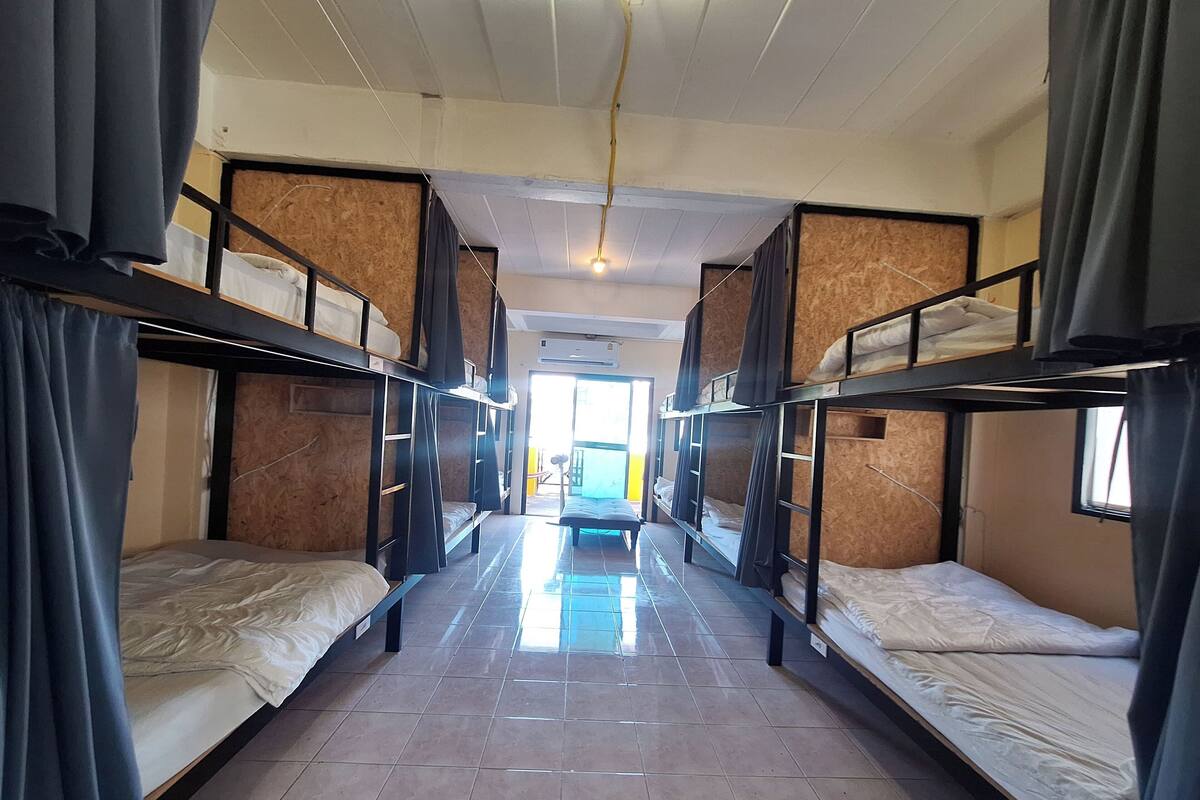A corridor with bunk beds, tiled flooring, and a ceiling fan.