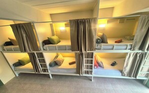 Ein Schlafraum im Schlafsalstil mit Etagenbetten, jeweils mit Kissen und Decke.