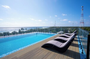 Una piscina al aire libre, sombrillas, sillones reclinables de piscina