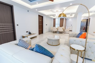 A modern living room with a sofa, coffee table, and a dining area in the background.
