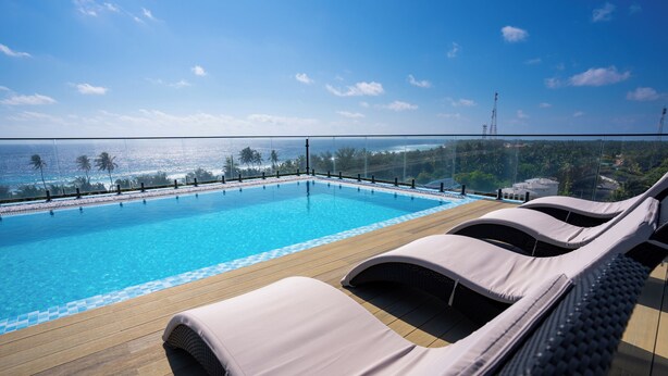 Un área junto a la piscina con sillas de descanso y vistas al océano.