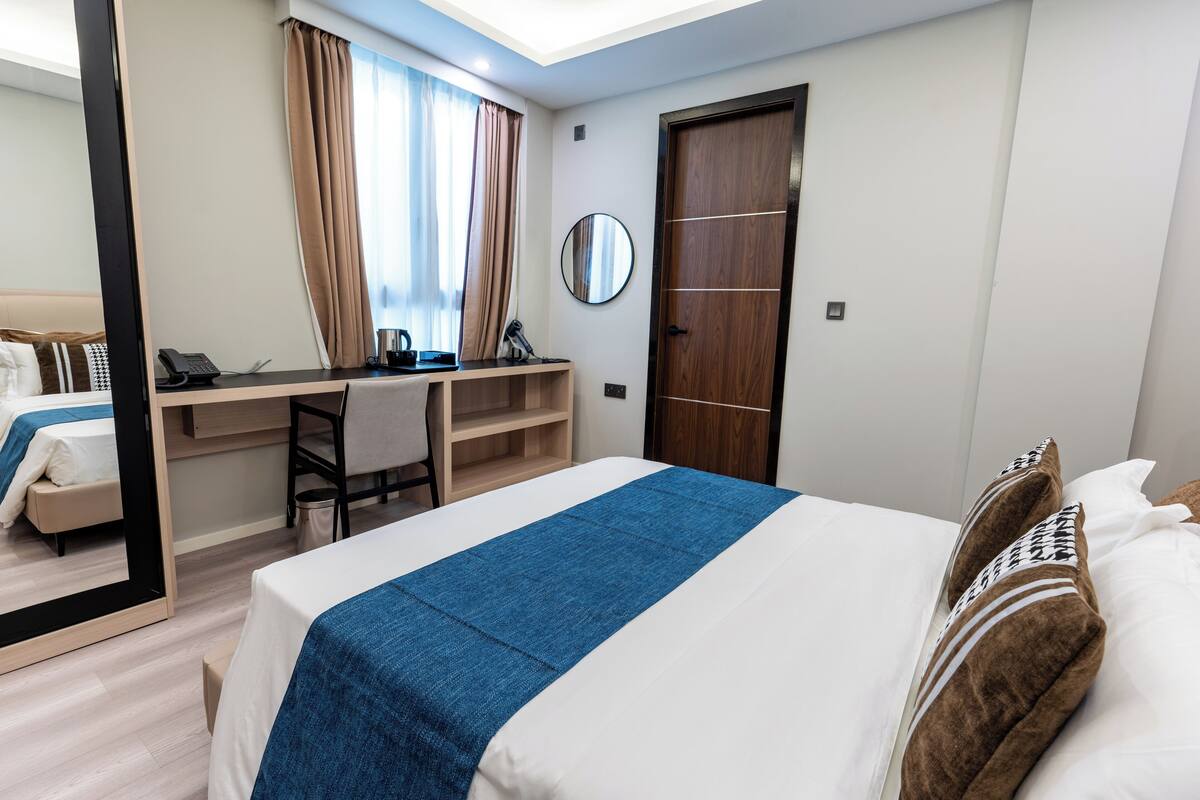Een hotelkamer met een bed, een bureau, een stoel, een spiegel en een kledingkast.