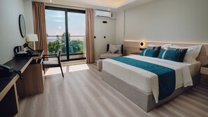 Una habitación de hotel moderna con una cama grande, un escritorio y un balcón con vistas.