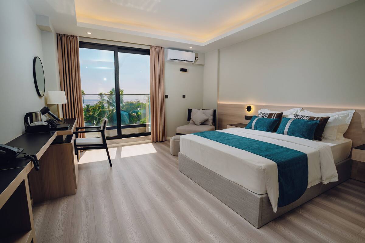 Een moderne hotelkamer met een groot bed, een bureau en een balkon met uitzicht.