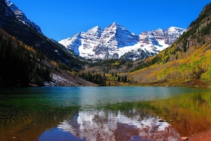 A mountain lake with clear reflections, surrounded by forested slopes and snow-capped peaks. - 2 Bedroom Condo at Historic Lift 1A in Downtown Aspen (Aspen)