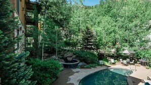 A swimming pool surrounded by lush greenery, with a patio area and outdoor furniture. - 3 Bedroom Condo at Historic Lift 1A in Downtown Aspen (Aspen)