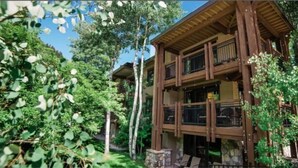 A multi-story wooden building with balconies, surrounded by lush greenery and trees. - 3 Bedroom Condo at Historic Lift 1A in Downtown Aspen (Aspen)