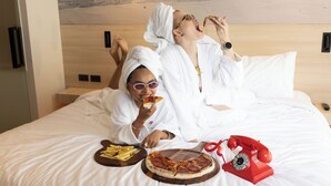 A bed with a pizza and fries, a red telephone, and a painting of a beach. - Radisson RED Phuket Patong Beach (Patong)