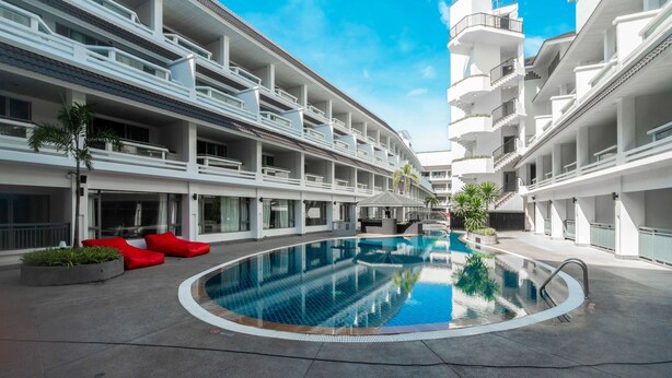 A modern hotel with a central swimming pool, multiple balconies, and a clear blue sky. - Radisson RED Phuket Patong Beach (Patong)