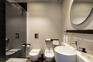 Een moderne badkamer met douche, toilet, bidet en een groot wastafel.