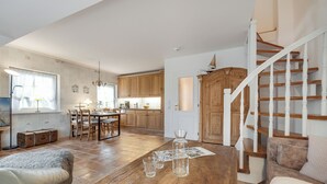 A spacious living room with a wooden coffee table, a sofa, and a staircase leading to a loft bedroom. - Green Teft - thatched house in the southwest part of the village of Keitum (Sylt / OT Keitum)