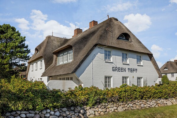 A traditional house with a steeply pitched thatched roof and white walls, labeled "GREEN TEFT."