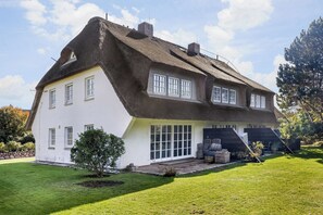 A house with a steeply pitched roof, large windows, and a well-maintained lawn.