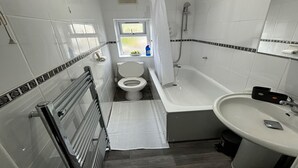 A modern bathroom with a toilet, bathtub, and sink.