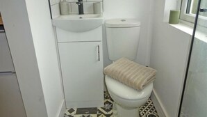 Casa de banho compacta com sanita, lavatório e uma pequena janela.