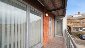 Uma varanda com janelas amplas, uma parede de tijolos e um deck de madeira.
