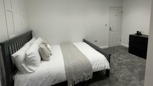 Quarto com cama, cômoda e porta.