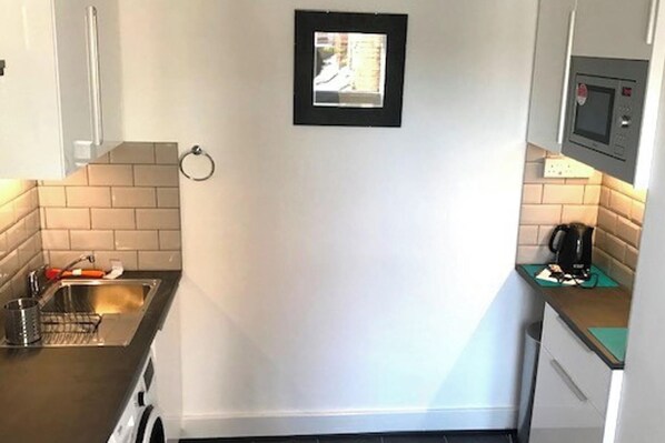 A small kitchen with a sink, a coffee machine, and a framed picture on the wall. - Cozy Quiet City Escape - Northampton Apartment (Northampton)