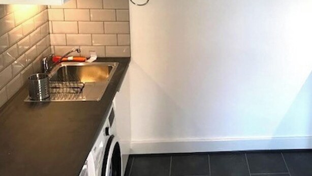 A kitchen with a stainless steel sink, a metal colander, and a white appliance.