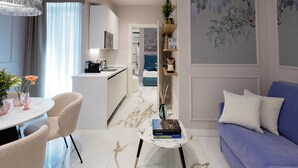 A modern living room with a blue sofa, a white coffee table, and a dining area with a white table and chairs. - SUITE CLARICE & LUCREZIA Le 5 Lampade Florence (Firenze)