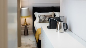 A modern hotel room with a white bed, a black headboard, a small bedside table with a lamp, and a kettle on the nightstand. - SUITE CLARICE & LUCREZIA Le 5 Lampade Florence (Firenze)