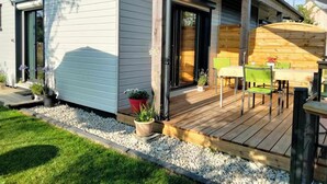 Et moderne hus med træterrasse, udendørs møbler og plantekasser.