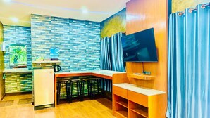 Cocina compacta de diseño moderno, con refrigerador empotrado, cafetera y televisor de pantalla plana montado en la pared.