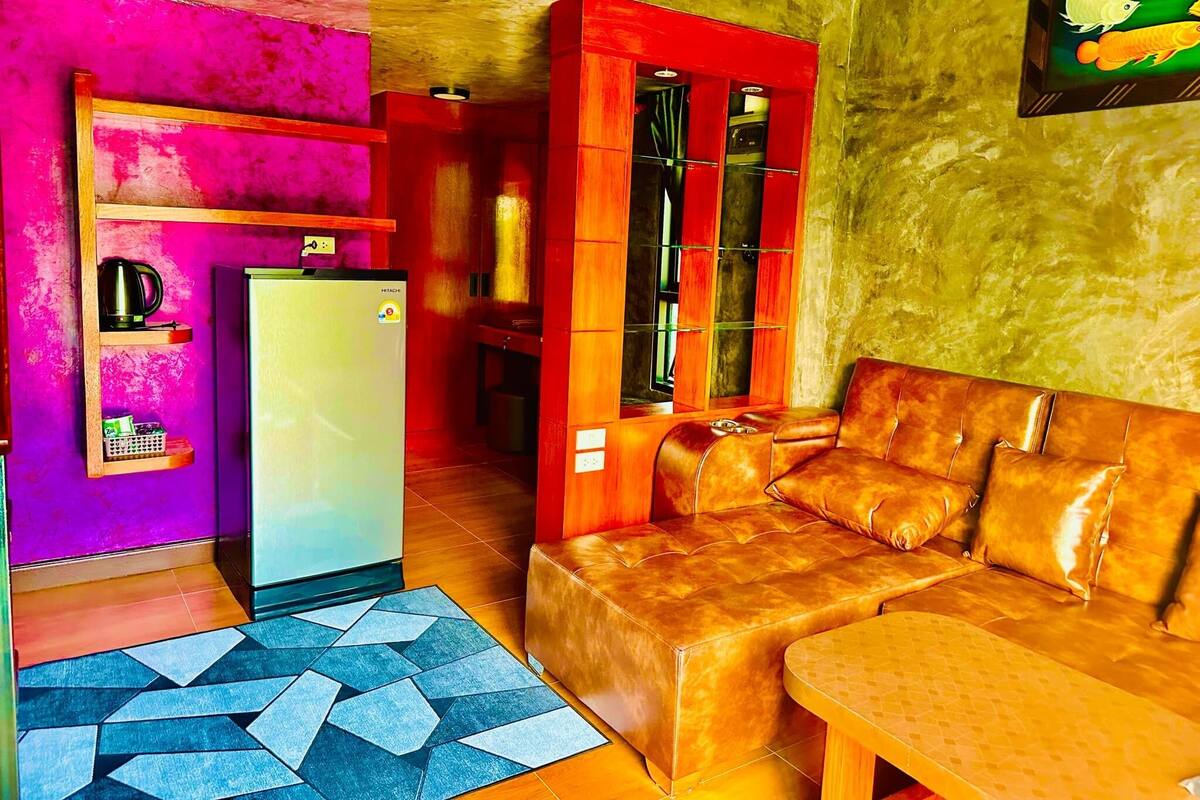A living room with a sofa, a coffee table, a refrigerator, and a cabinet with glass doors.