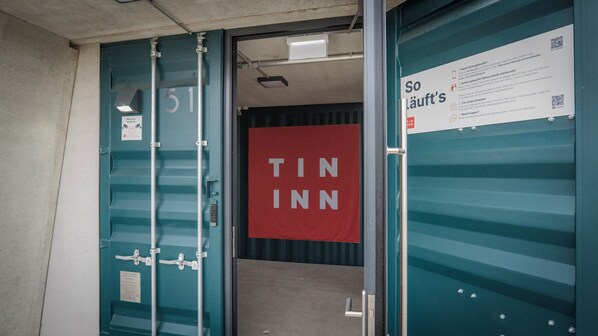 En hotellentrédörr med en röd skylt som visar texten ”TIN INN” och en informationsskylt med text och en QR-kod.
