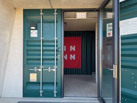 Una puerta verde con una placa de número, un cartel rojo y una puerta de cristal con un letrero.