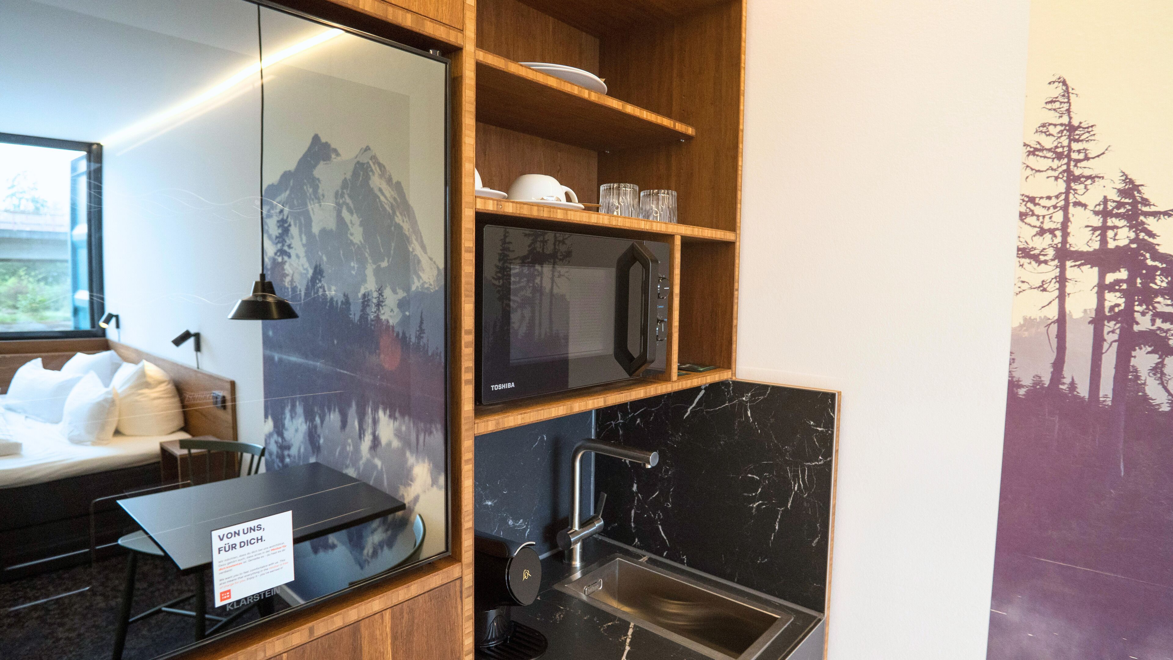 Una cucina compatta con forno a microonde, lavello e mensole in legno.