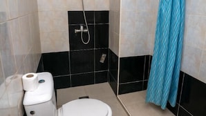 A small bathroom with a toilet, a shower, and a blue patterned shower curtain. - Hotel Alecanti (Beni Mellal)