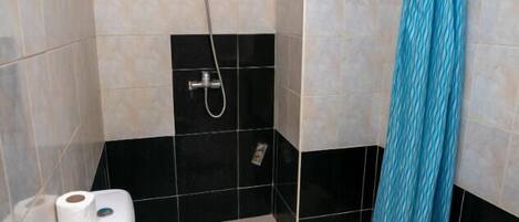 Un baño pequeño con inodoro, ducha y cortina de ducha azul estampada.