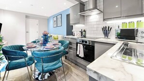 A modern kitchen with teal chairs, a built-in oven, and a microwave. - Tranquility in Bloom: Refreshing 2BR Apartment (London)