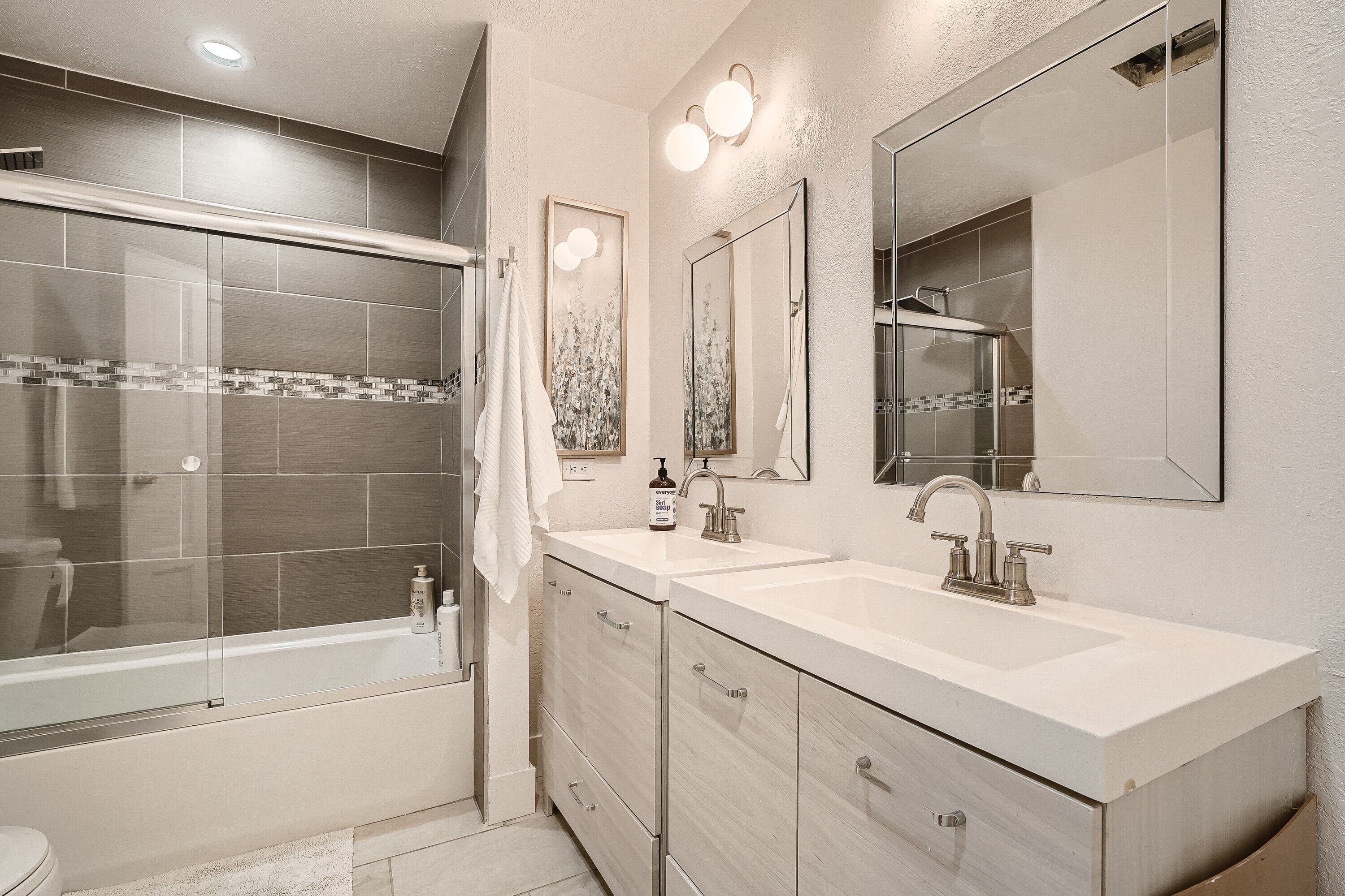 A modern bathroom with a glass-enclosed shower, a double sink vanity, and a large mirror.