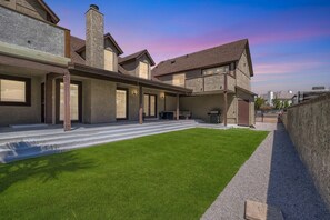 A modern house with a covered patio, a well-maintained lawn, and a stone chimney. - Spacious Villa 20 min to Strip & Airport!  Private Pool and amenities for all ages! (Las Vegas)