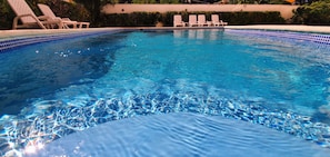 A swimming pool with clear water, surrounded by lounge chairs.