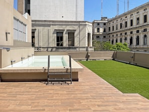 A rooftop pool with a wooden deck, surrounded by a well-maintained lawn and classical architecture. - Modern Studio With Amenities in the Heart of the City (Buenos Aires)