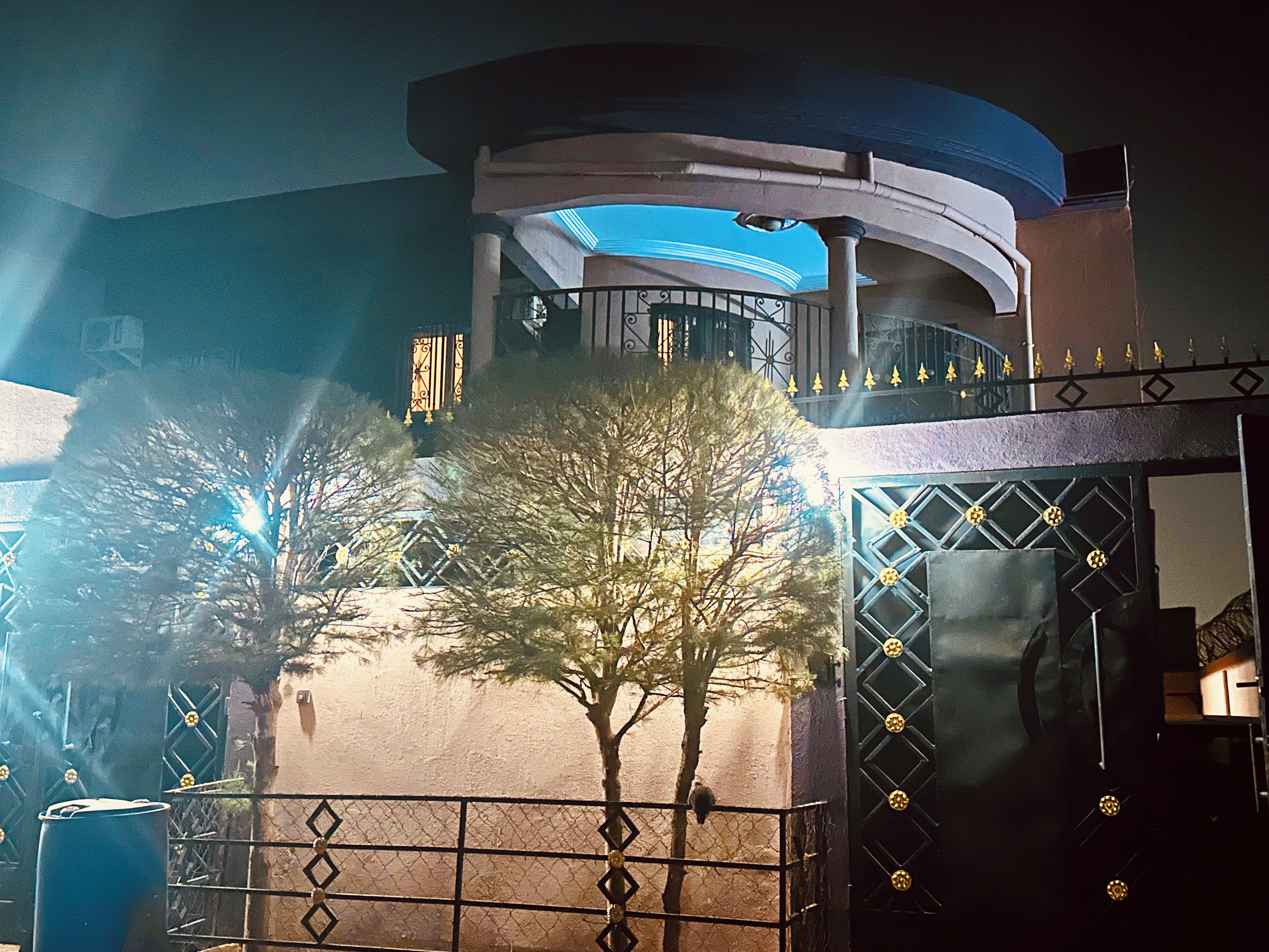 A building with a circular structure, a gated entrance, and a tree in the foreground.