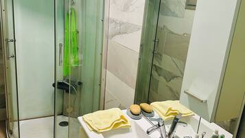 A bathroom with a glass-enclosed shower, a sink with toiletries, and a mirror.